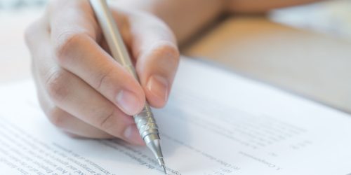 Hand with pen over application form