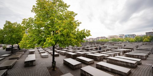 Memorial to the Murdered Jews of Europe in Berlin downtown, Germany. Rows of rectangular concrete blocks with narrow alleys between them, trees